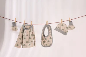 Baby bodysuit, bib, hat and booties clipped to a clothesline against a pale background