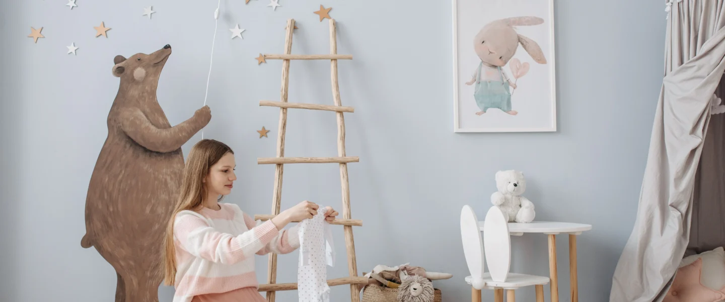 Newborn clothing checklist: parent organizing baby clothes in a nursery